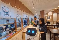 Pelayanan sedang meletakkan makanan di atas robot untuk diantar ke meja pengunjung. Foto: Fakhrur/intimes.co.id